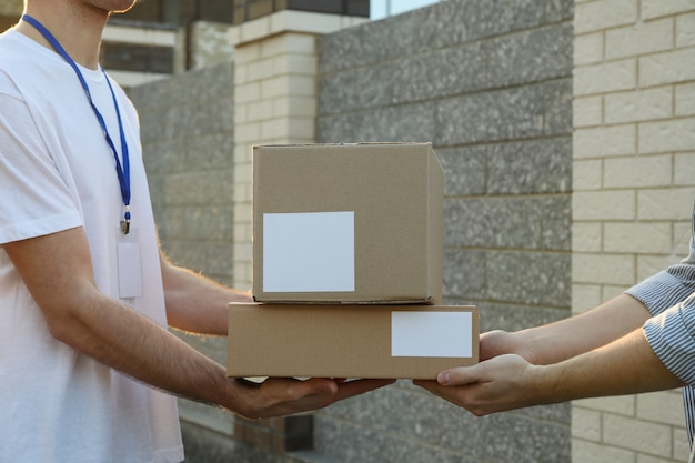 Man receiving boxes from delivery man outdoor, blank space