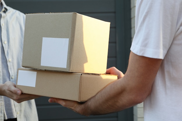 Photo man receiving boxes from delivery man outdoor, blank space