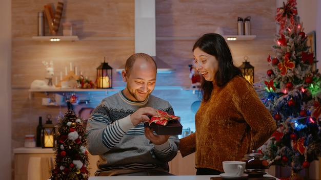 Man receiving gift from woman on christmas eve day