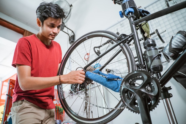 Uomo in abiti rossi che lavora per riparare un problema all'asse della bicicletta con una chiave inglese