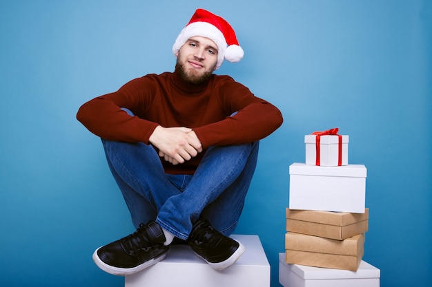 A man in a red hat sits next to New Year's gifts