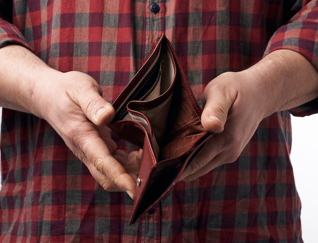 Man in a red plaid shirt holds an empty leather brown wallet