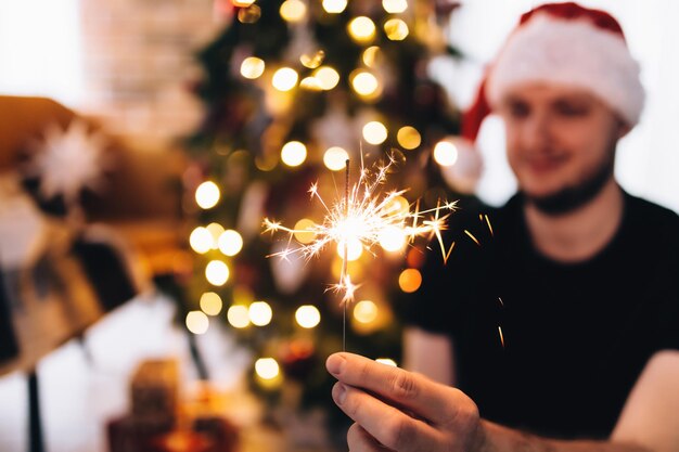 Photo man in red santas hat with sparkler high quality photo