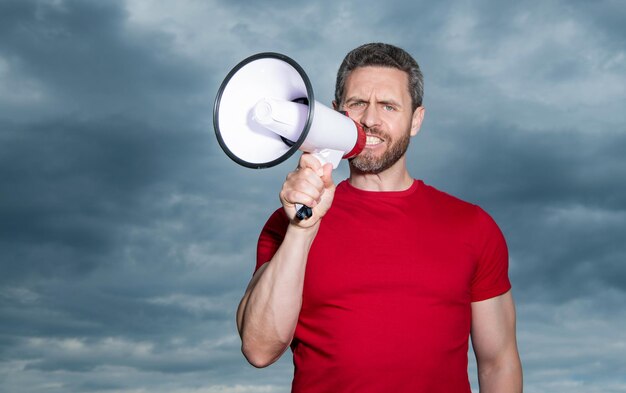 Man in red shirt announce in loudspeaker on sky background