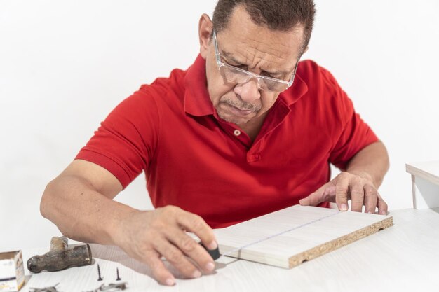 Foto uomo in camicia rossa che misura e segna il legno per un accurato assemblaggio di mobili