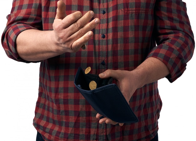 L'uomo in una camicia rossa versa monete in grivna da un portafoglio in pelle marrone nella sua mano