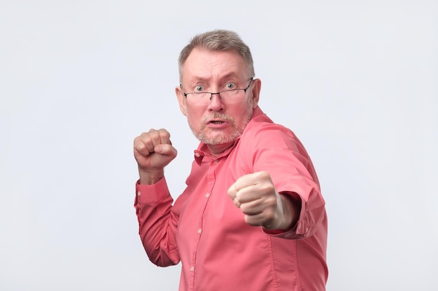 Man in red shirt standing in boxer pose with raised fists as if defending