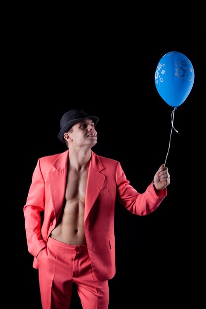 Foto uomo in abito rosso con palloncino blu