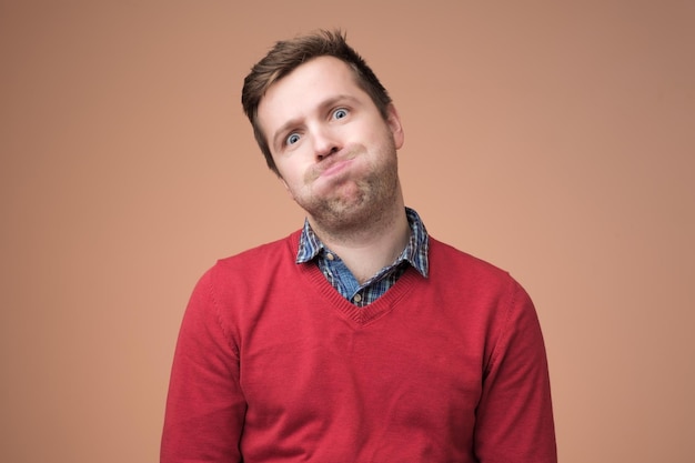 Man in red sweater puffing his cheeks feeling fed up as heis tired