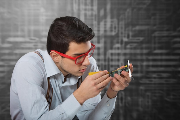 Man in redframed glasses looking at the microprocessor in his hand