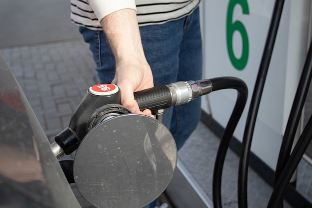 A man refueling the car on gas station. Petrol Station. Gas pump close up. An automobile is getting refueled by a petrol pistol.