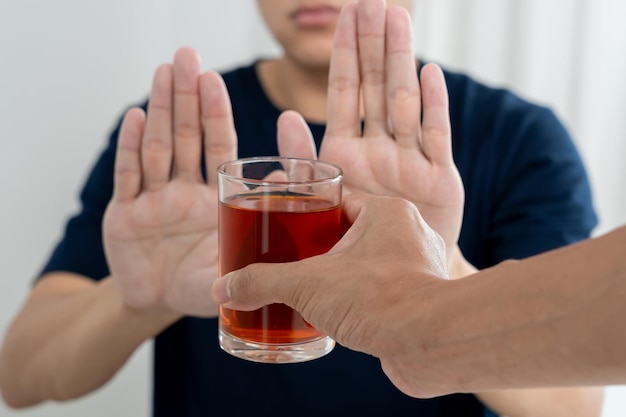 写真 男性はノーと言って拒否し、アルコールを飲むのを避ける ウイスキー ストップハンドサイン 男性アルコール依存症の治療 アルコール依存症 酒をやめる 飲酒をやめる アルコールを拒否する グラスのお酒 不健康な拒否