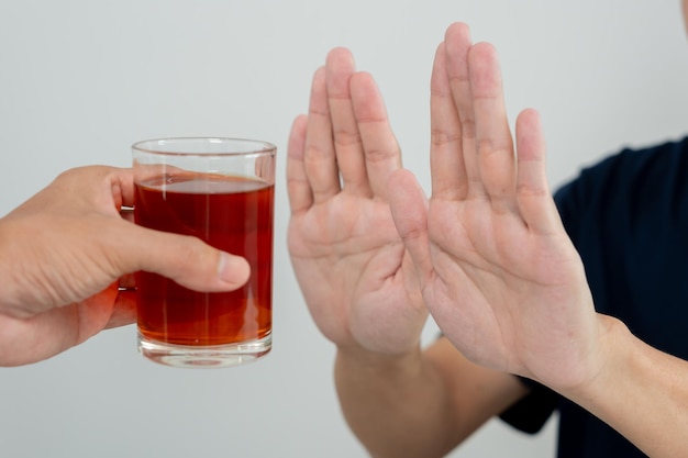 男性は飲酒を拒否し飲み物を飲むのを避けます ウイスキーを止めます 手を振って男性のアルコール依存症の治療を拒否します アルコール中毒酒をやめます 飲酒をやめる 拒否する グラス酒は不健康です 拒絶します