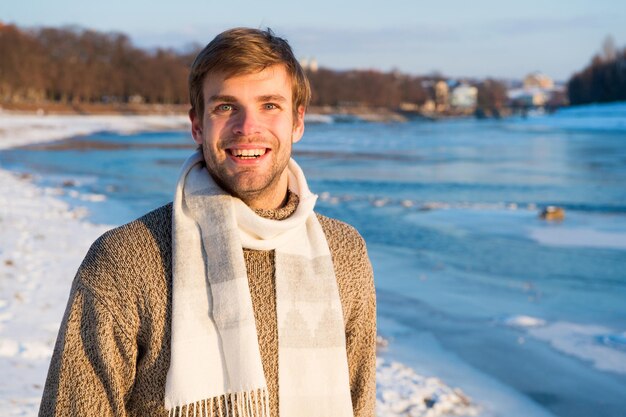 Man reizen in de winter, natuur. Warme kleding voor het koude seizoen. Sexy man in winterkleren. Wintermode. warme trui en sjaal. Fijne wintervakantie. Griep en verkoudheid. Kerst vakantie. Warme glimlach.