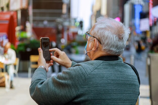 Man reizen kijken in smartphone van Times Square, Manhattan, New York City op het dragen van een gezichtsmasker