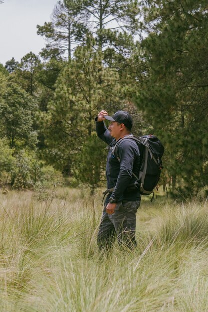 Man reiziger alleen met rugzak kijken naar berg tussen groene bossen