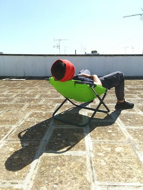 Foto uomo che si rilassa sulla poltrona in terrazza durante la giornata di sole