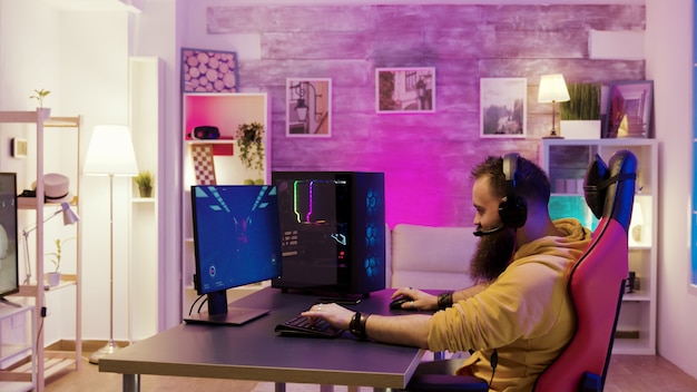 Man relaxing playing video games after a stressful day at work. Room with colorful neon lights.