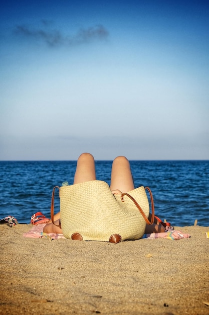 Foto uomo che si rilassa sulla sabbia sulla spiaggia contro il cielo