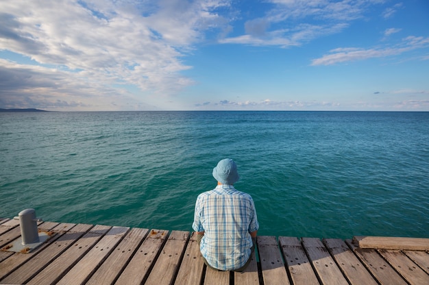 Foto uomo che si distende sul molo sul mare