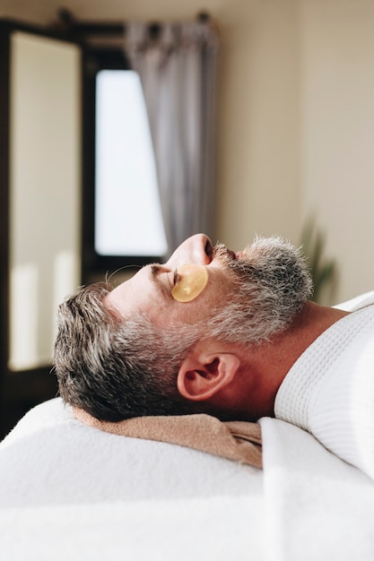 Foto uomo che si rilassa con un trattamento di maschera d'oro