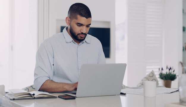 Man remote work and typing at laptop in home for digital planning online research and information at table Male freelancer working on computer technology internet and reading email for budget