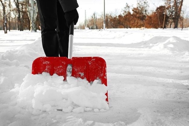 Foto uomo che rimuove la neve con la pala rossa