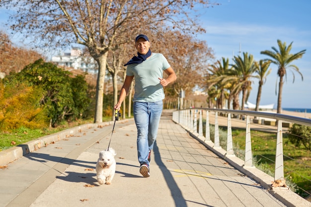 Man rent met zijn hond in het park.