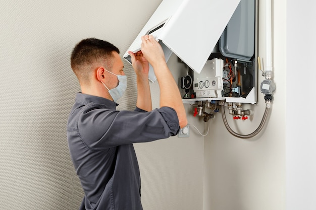 A man repairing a boiler in a medical mask