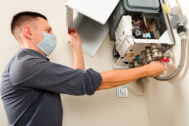 Photo a man repairing a boiler in a medical mask