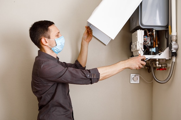 A man repairing a boiler in a medical mask