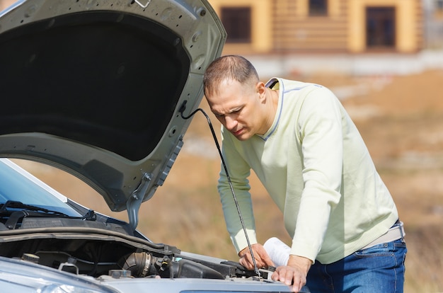 Man repairing a broken car on the road