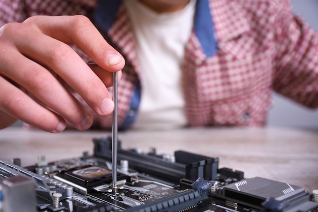 Man repairing broken computer, video card,memory RAM, cooler, processor,hard drive.Young repairer working with screwdriver in service center.teenager