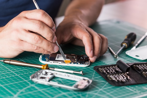 Man repairing broken smartphone, close up photo.