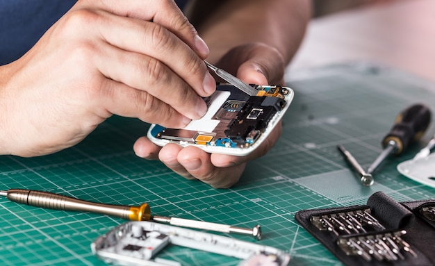 Photo man repairing broken smartphone, close up photo.