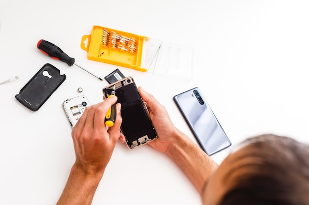 Man repairing broken smartphone in workshop