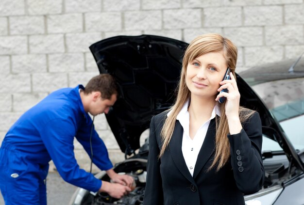 ビジネスの女性の車を修理する男