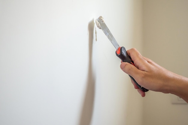 Man repairing crack white wall with spatula