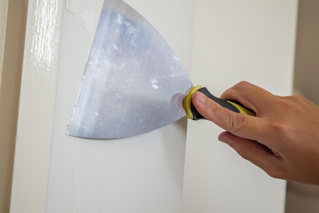 Man repairing crack white wall with spatula