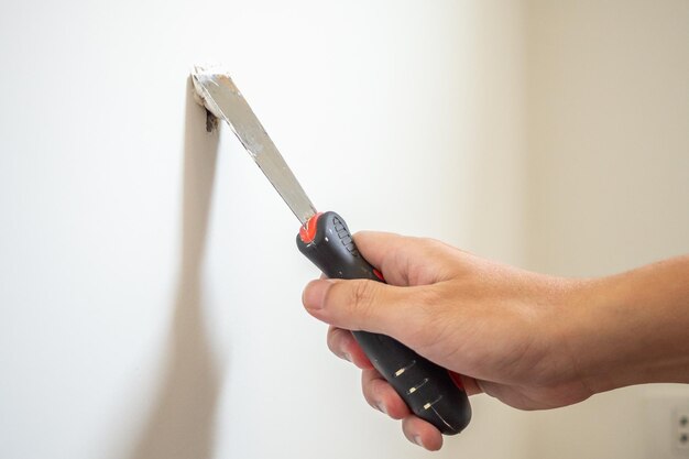 Man repairing crack white wall with spatula