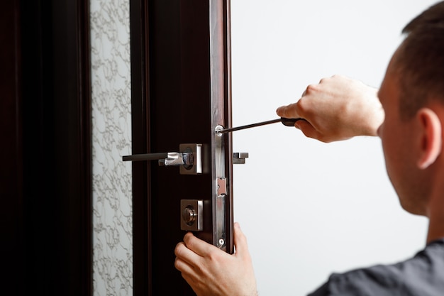 Man repairing the doorknob. Carpenter working on lock installation with out the door knobs wood door