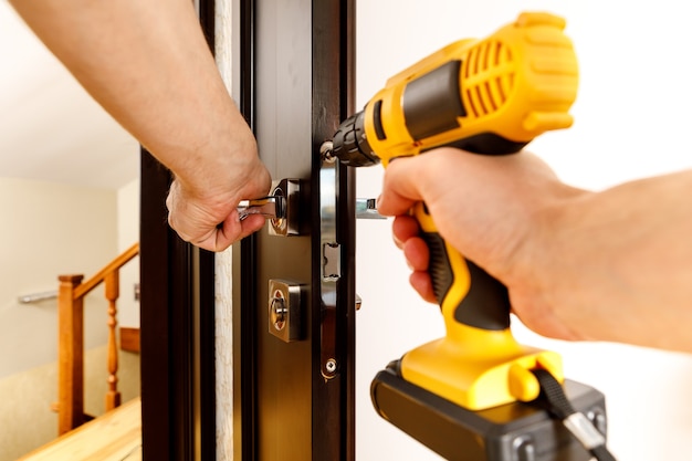 A man repairing a doorknob. Handyman repair the door lock in the room