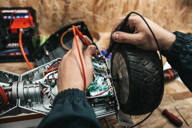 特別なワークショップで電動スクーターを修理する男。電気スクーターと自転車を修理するための特別なワークショップ。