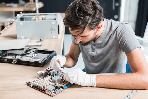 写真 コンピュータの電子回路を修復する男