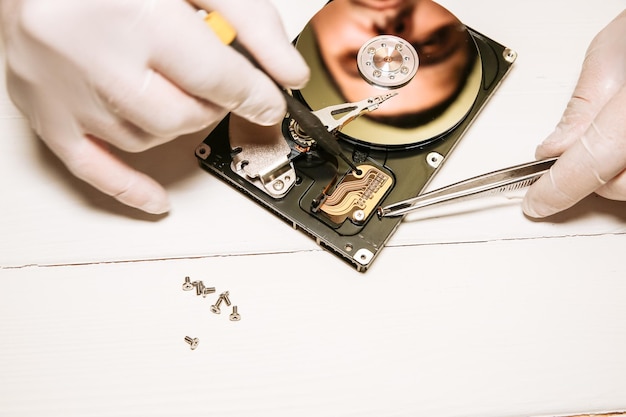 写真 ハードディスクを修理する男性 古いパソコンの内部の詳細 壊れた pc スクリュードライバーとペンチを手に
