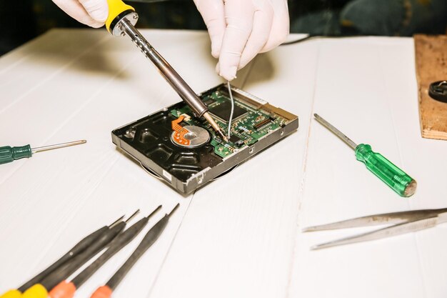 写真 ハードディスクを修理する男 古いパーソナルコンピュータの内部詳細 壊れたpc 手に溶接鉄