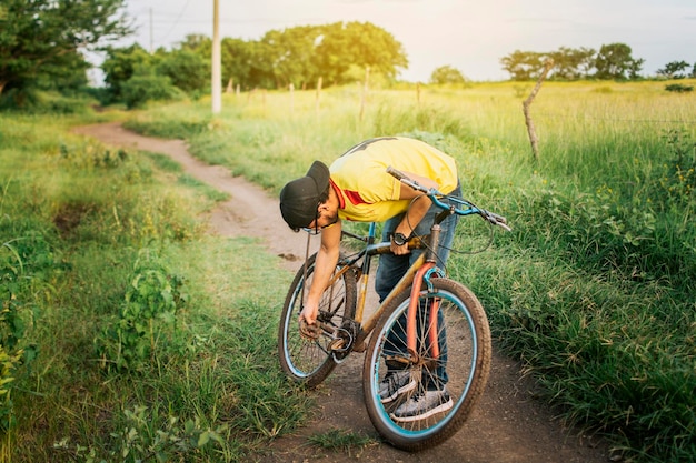 道の真ん中で自転車を修理する男性 田舎で自転車を修理する男性 道路で自転車を修理する旅行者