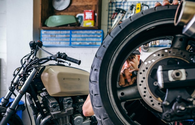 Foto uomo che ripara una moto in garage