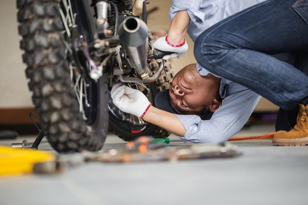 Foto uomo che ripara la motocicletta in officina riparazione meccanica della moto nel garage dell'officina concetti di riparazione e manutenzione