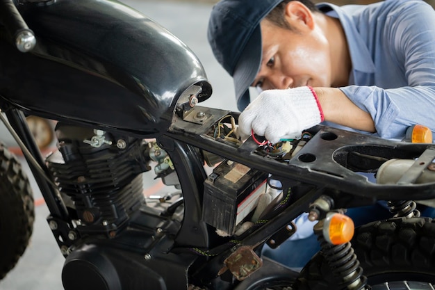 Man repairing motorcycle in repair shop Mechanic fixing motorbike in workshop garage Repairing and maintenance concepts